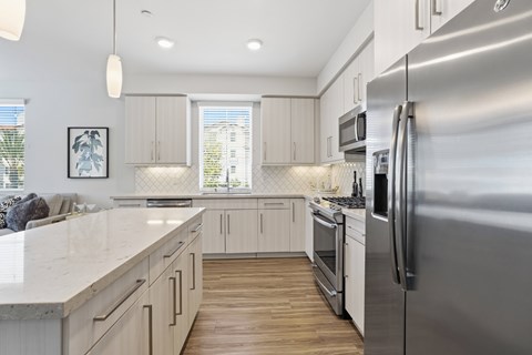A modern kitchen with a stainless steel refrigerator and wooden floors.