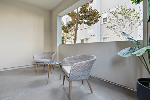 Two chairs and a table are on a balcony.