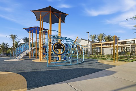 A playground with a blue and yellow slide and a brown and blue play structure.