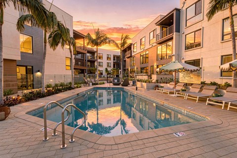 A swimming pool surrounded by palm trees and lounge chairs.