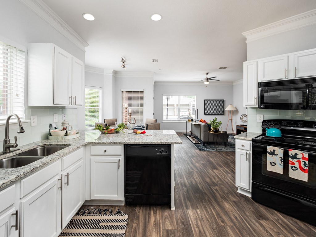 a large kitchen with white cabinets and black appliances