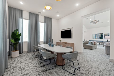 A modern dining room with a large table and grey chairs.