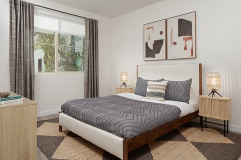 A bedroom with a large bed and two lamps.
