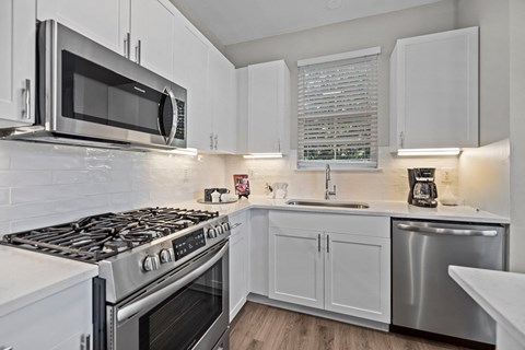 A modern kitchen with white cabinets and stainless steel appliances.