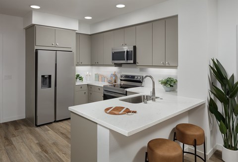 A modern kitchen with a white countertop and stainless steel appliances.