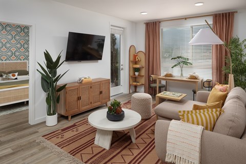 A living room with a television, a couch, and a potted plant.