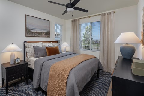 A bedroom with two beds, a ceiling fan, and a painting on the wall.