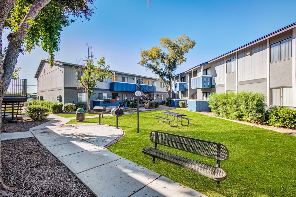 a park with a bench and picnic table in front of a building