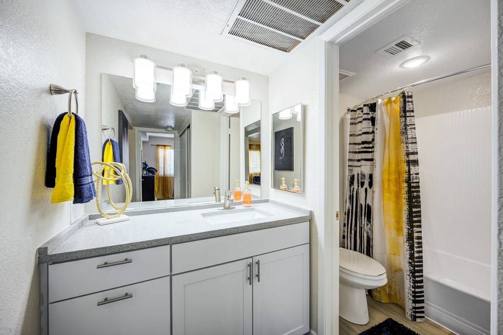 a bathroom with white cabinets and a yellow shower curtain
