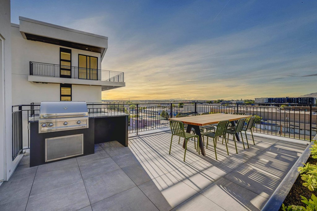 A patio with a table and chairs and a grill.