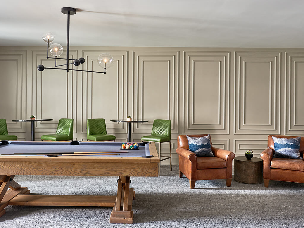 a living room with a pool table and chairs