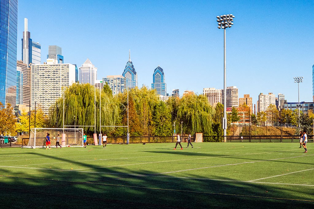 a group of people playing soccer on a field with a city in the background