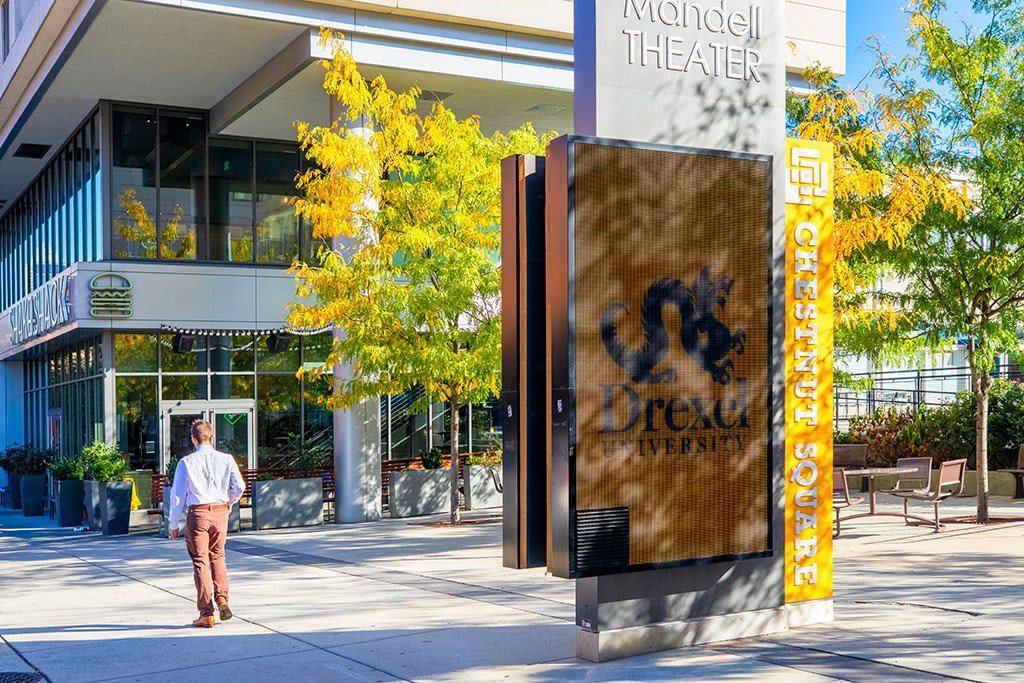 a man walking past a sign in front of a building