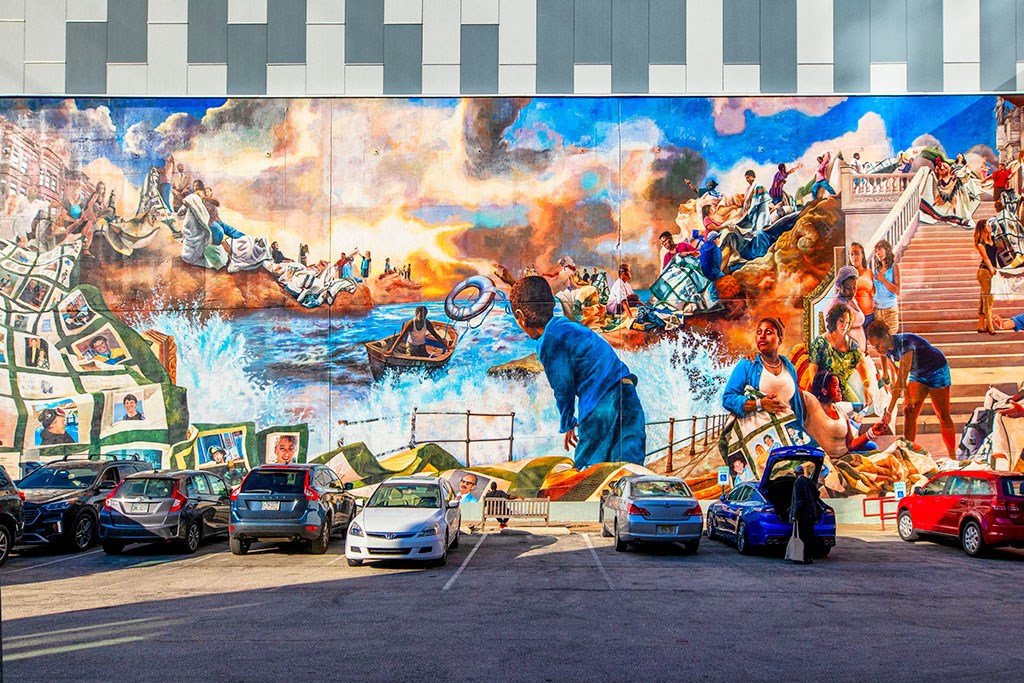 a mural on the side of a building with cars in front of it