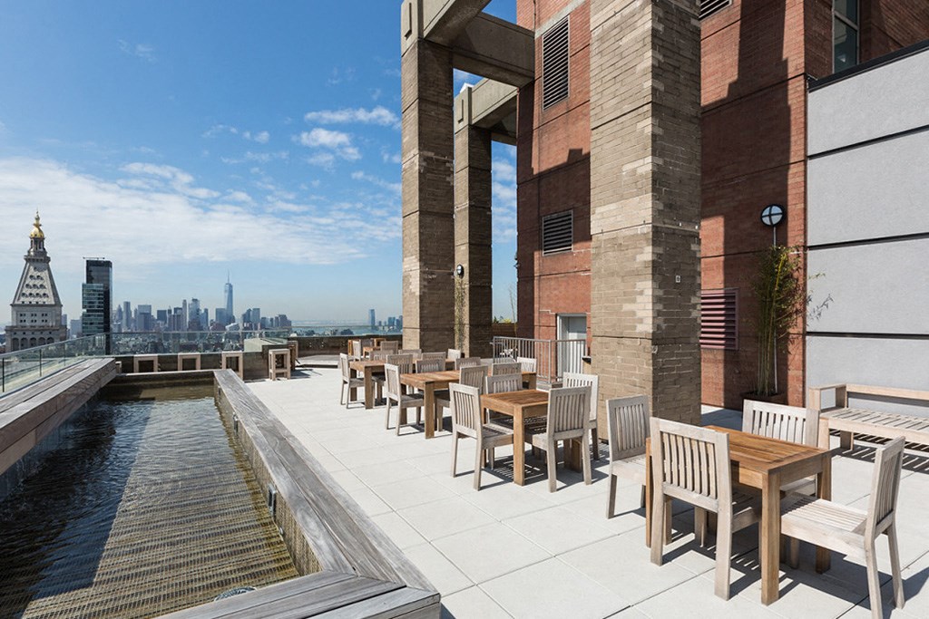 a rooftop patio with tables and chairs and a view of the city