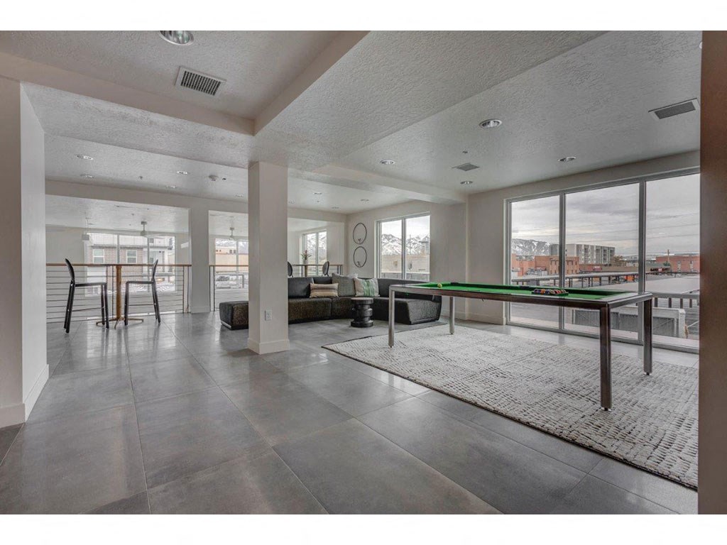 a spacious living room with a pool table and a view of the city