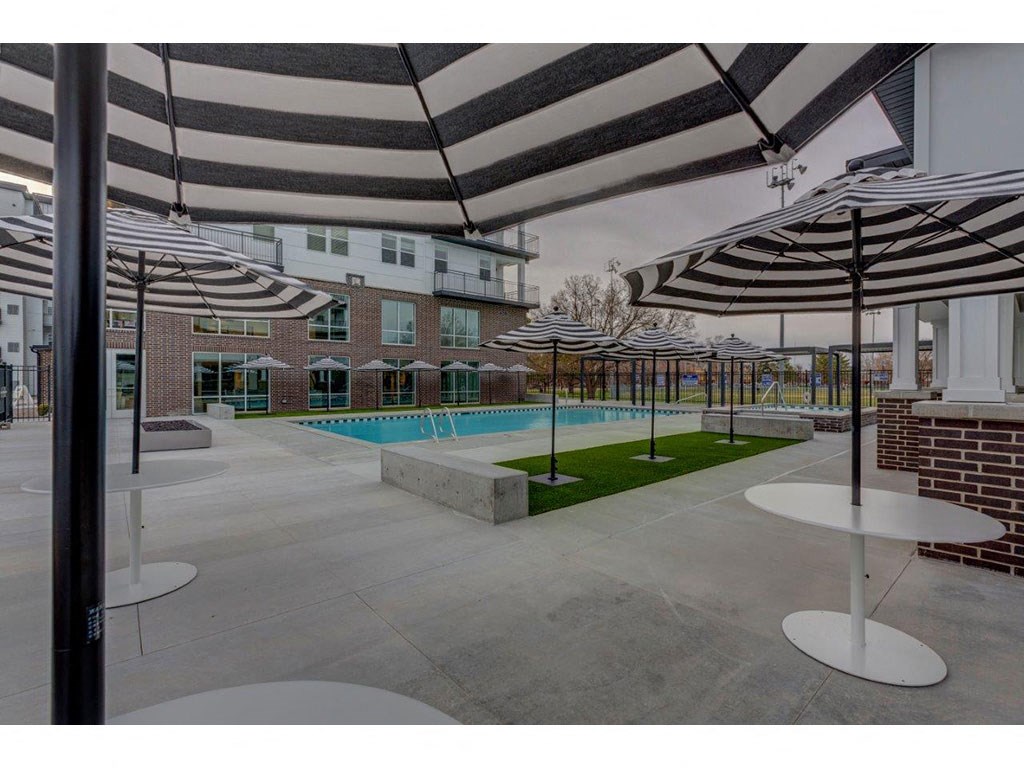 a pool and umbrellas in a courtyard with buildings
