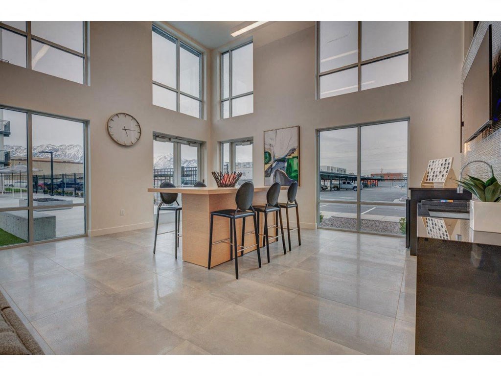 a living room with large windows and a counter with chairs