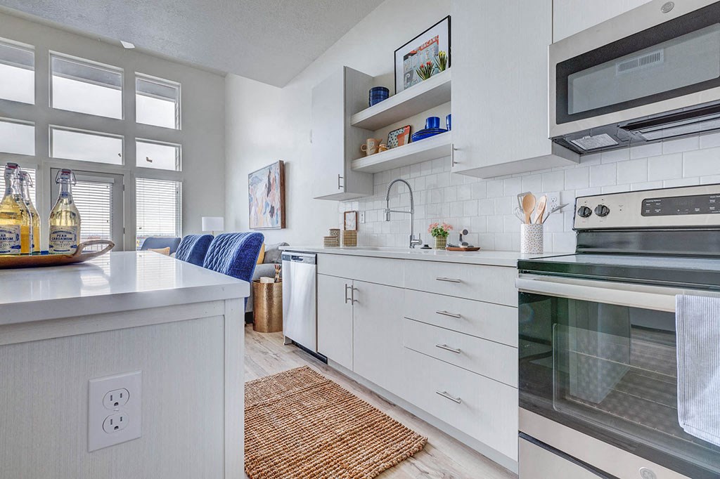 a white kitchen with stainless steel appliances and a window