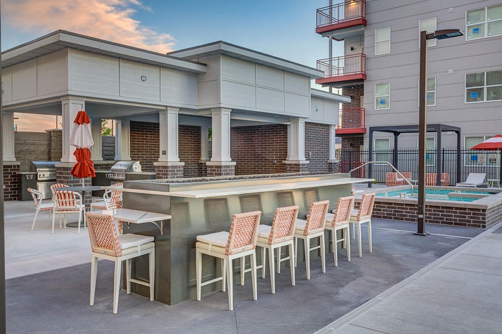 a patio with a bar and chairs in front of a building