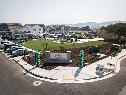 a park with a playground and cars parked in a parking lot