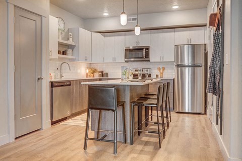 a kitchen with a center island and a stainless steel refrigerator
