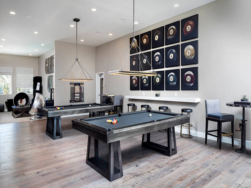 a game room with two pool tables and a wall of racked up pool balls