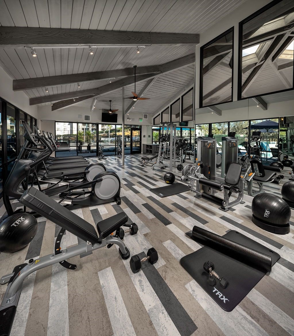 a gym with work out machines and windows