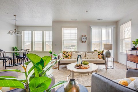 A living room with a couch, chairs, and a table with a vase on it.