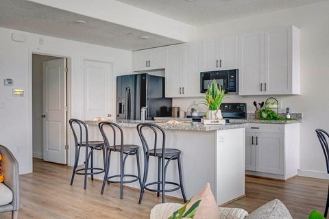 A kitchen with white cabinets and a black fridge.
