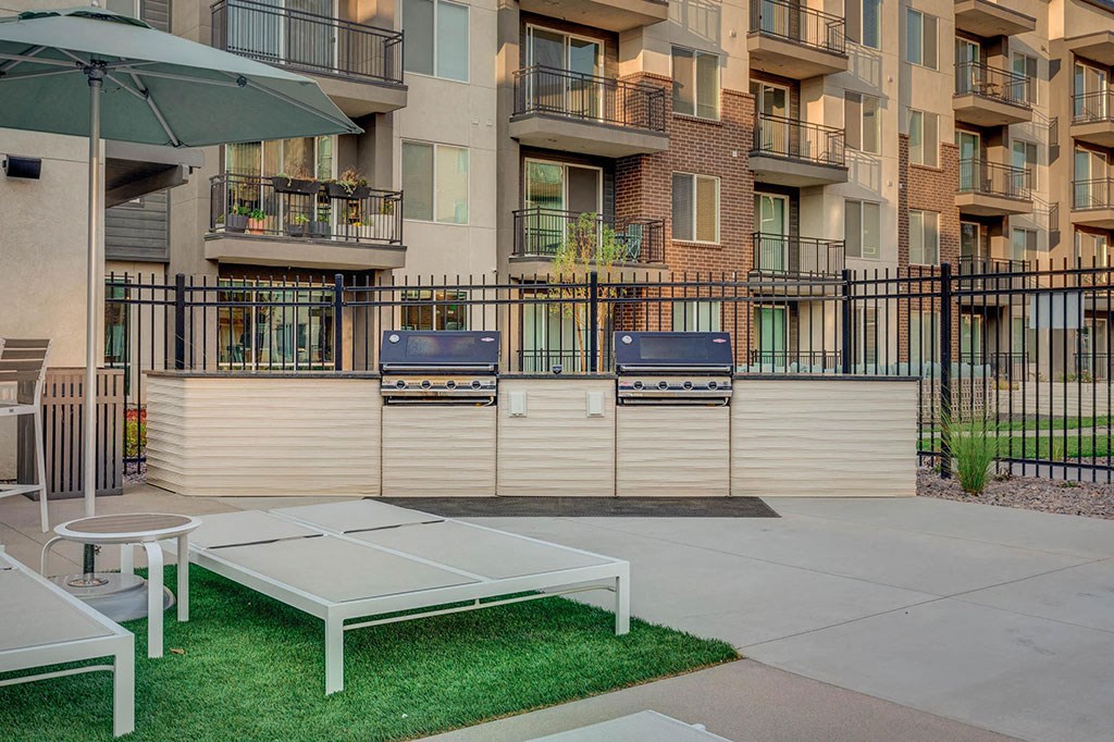 a patio with two tables and chairs in front of an apartment building