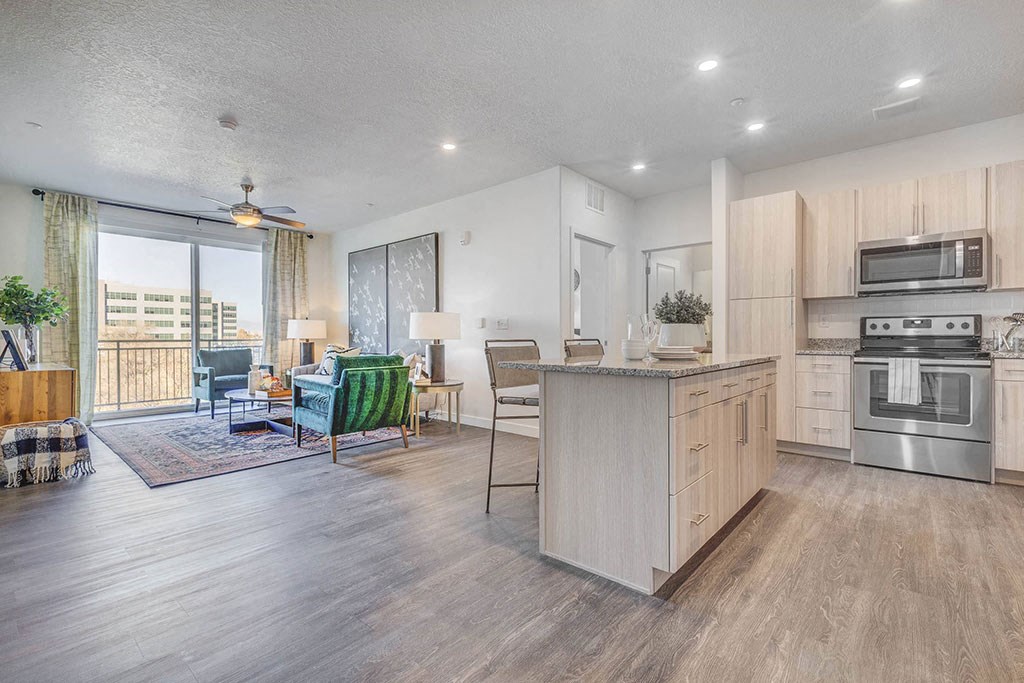 Kitchen looking out to living room- white cupboards, hardwood floors, stainless appliances