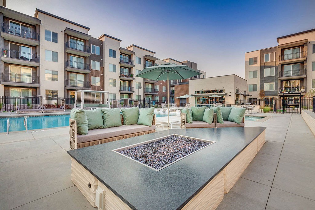 a patio with a table and chairs and a pool with an umbrella