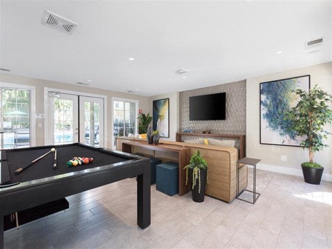 A room with a pool table and a television.