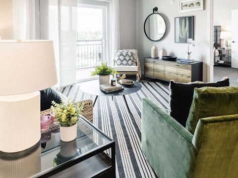 A living room with a green couch and a glass coffee table.