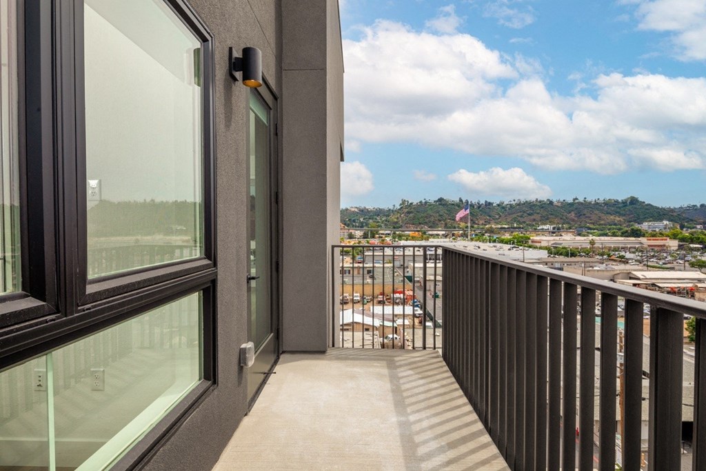 A balcony with a glass door and a view of a construction site.