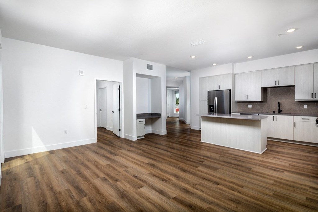 A kitchen with white cabinets and a wooden floor.