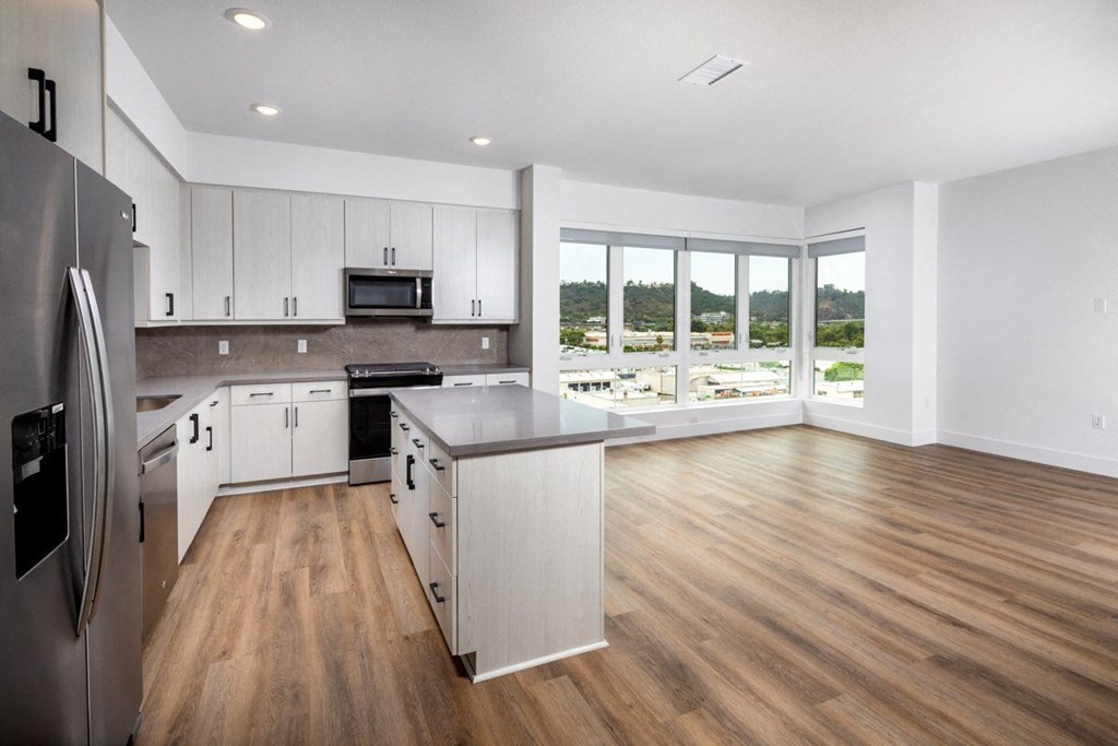 A modern kitchen with wooden floors and stainless steel appliances.