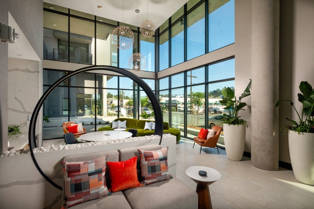A modern living room with a large window and a curved glass table.