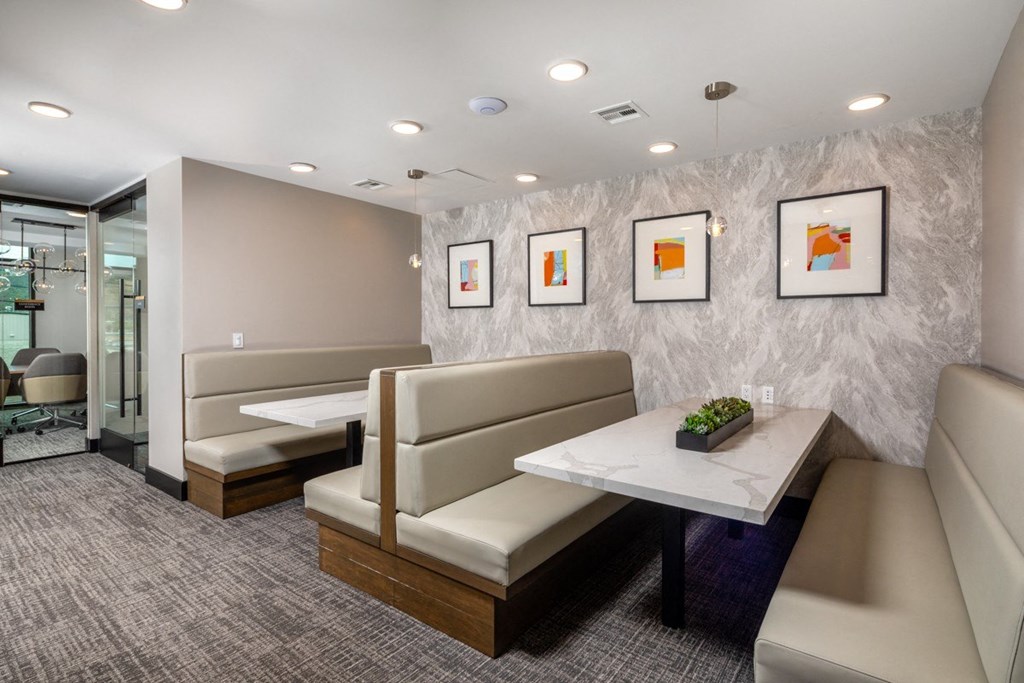 A modern waiting room with beige couches and a marble table.