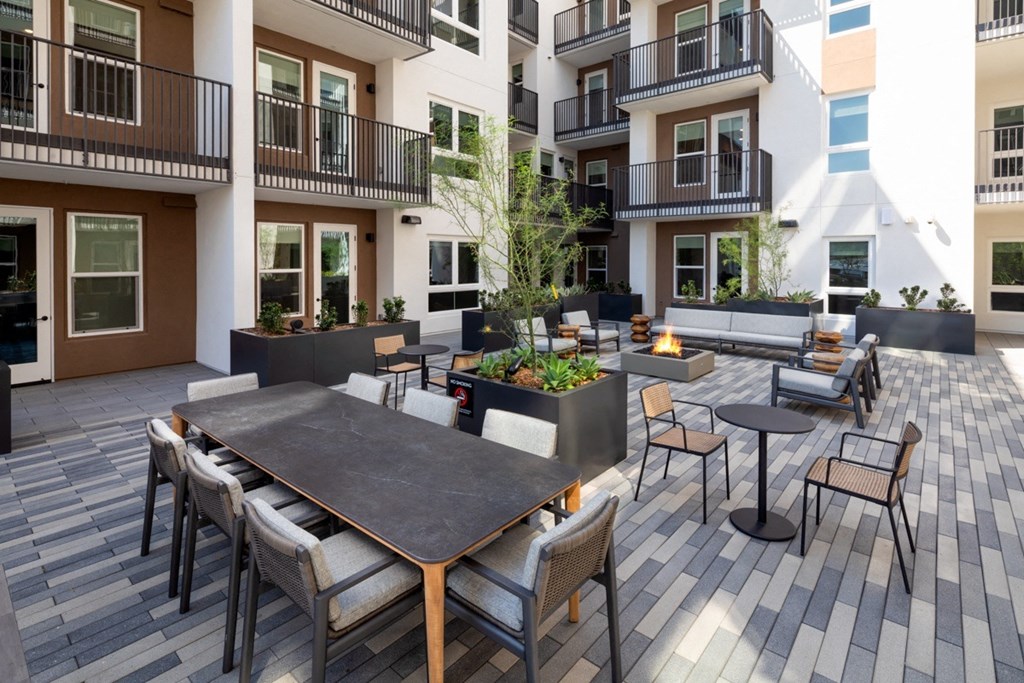 A patio with a table and chairs is surrounded by apartment buildings.