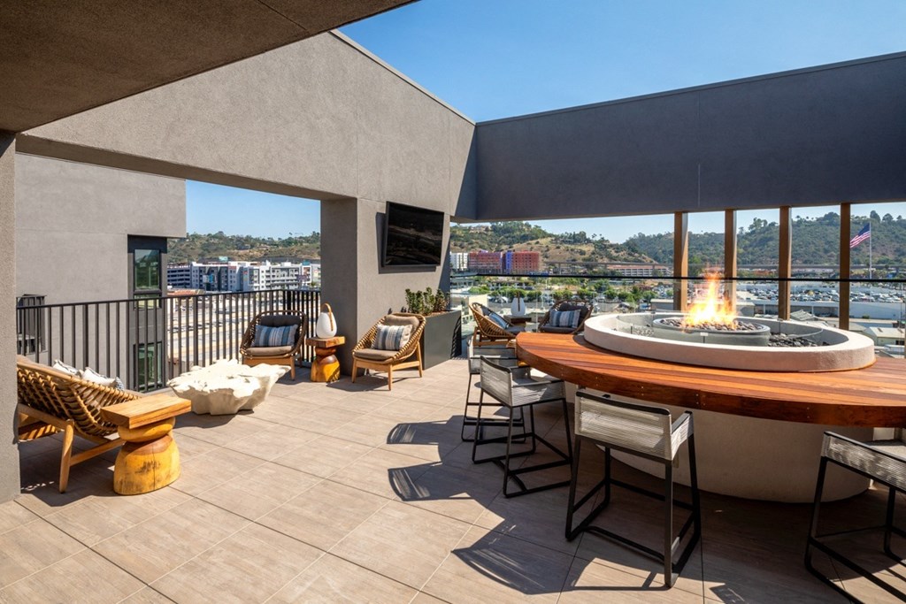 A patio with a fire pit and chairs.