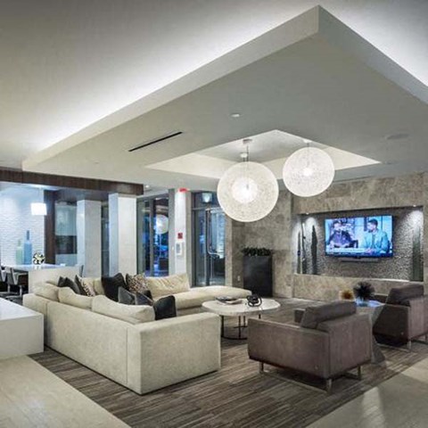 A modern living room with a large sectional sofa and a flat-screen TV mounted on the wall.
