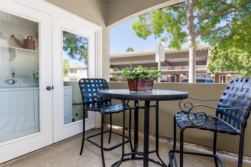 A patio with a table and chairs and a view of a building.
