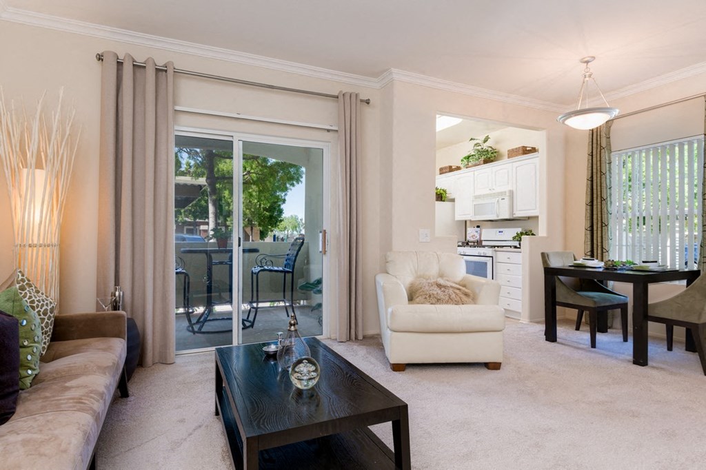 A living room with a couch, a chair, a coffee table, and a dining table.