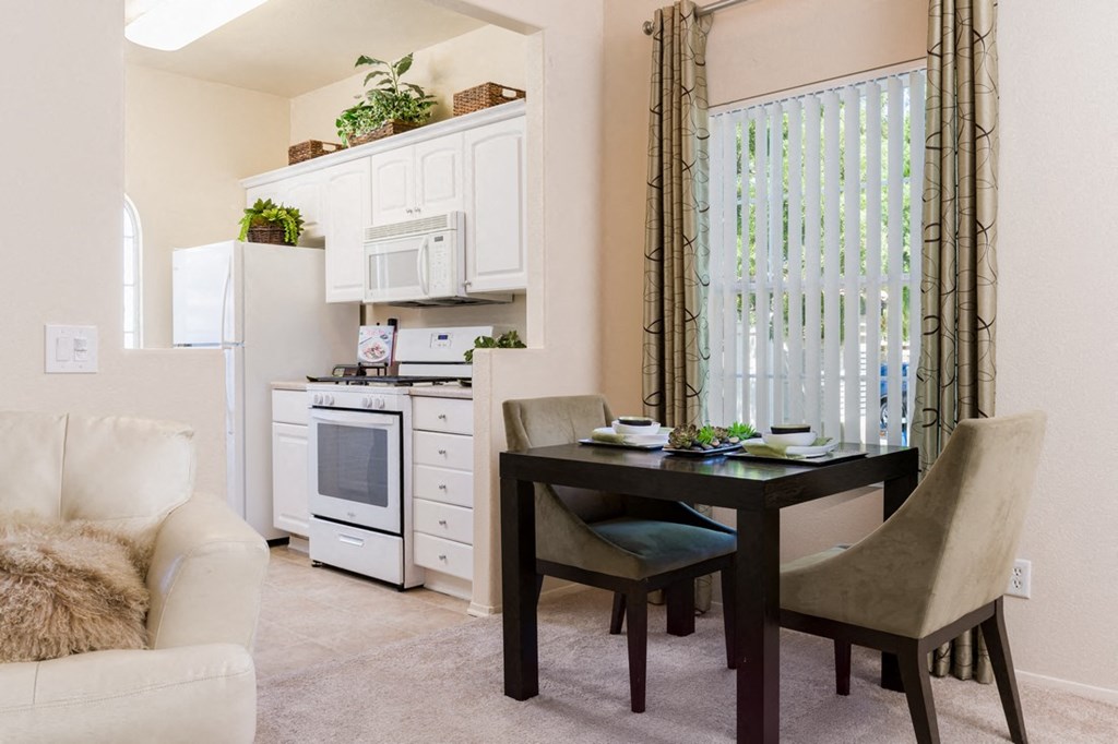 A kitchen with a table and chairs in front of a window.