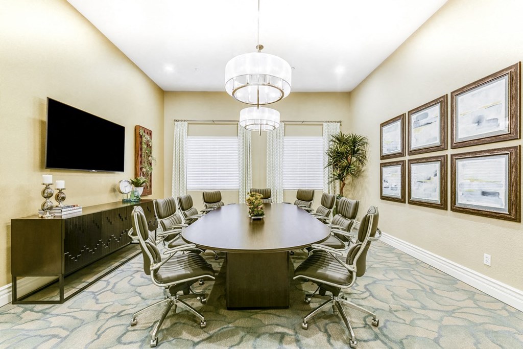 A conference room with a large table surrounded by chairs.