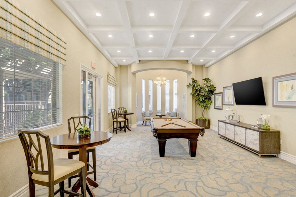 A well-lit room with a table, chairs, and a television.
