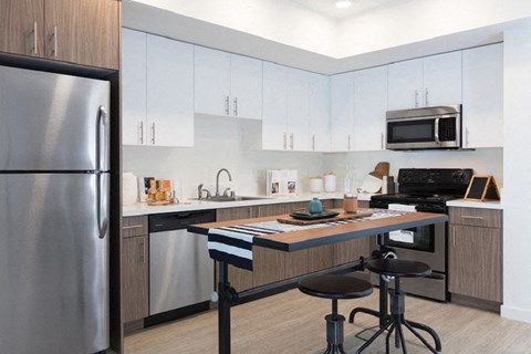 A modern kitchen with a stainless steel refrigerator and a wooden island.