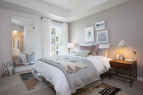 A bedroom with a large bed and a nightstand with a lamp.